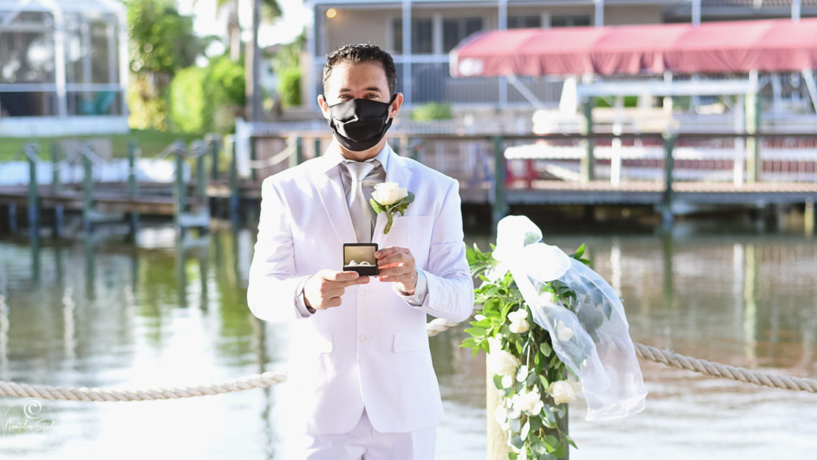 Foto de boda durante COVID 19 muestra al novio con máscara y anillos de boda