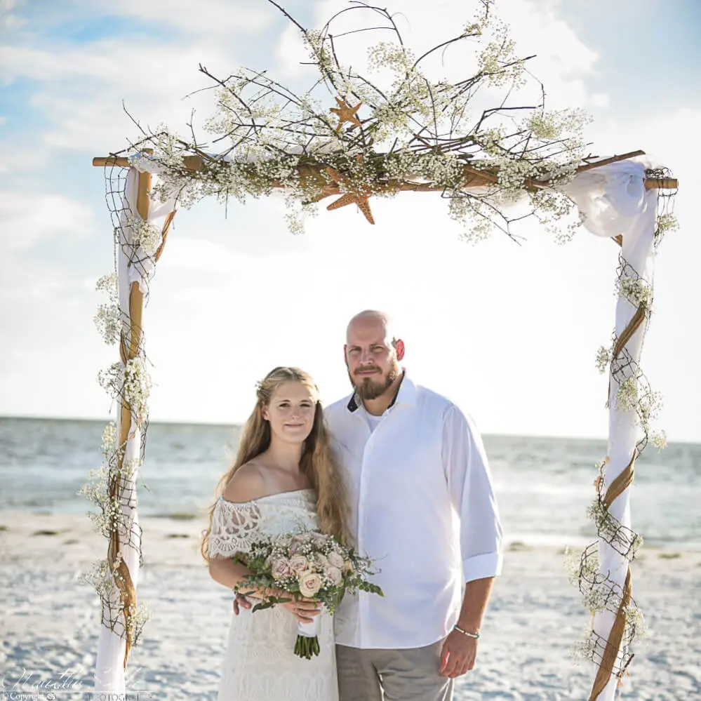 Bohemian Strandhochzeit Foto vom Brautpaar unter Boho Hochzeitsbogen