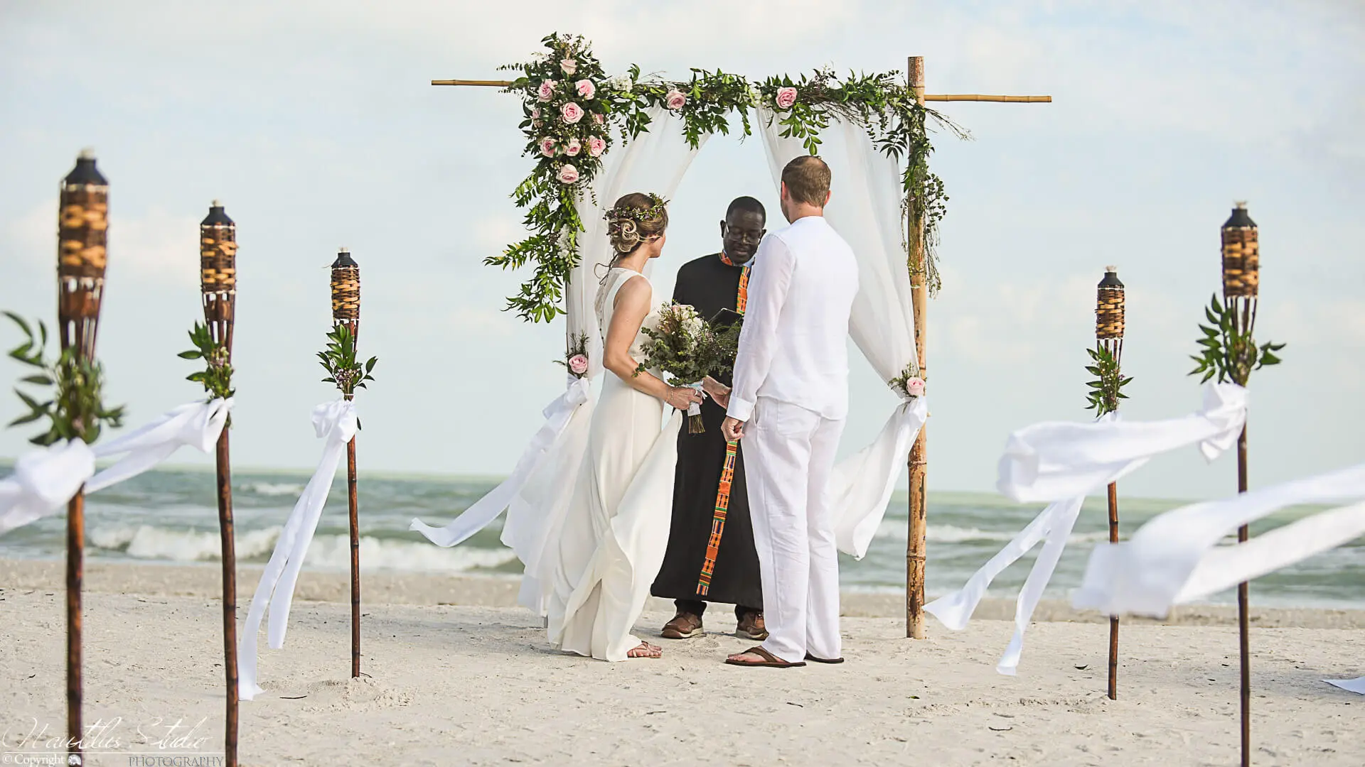 Boda vintage en la playa de Florida, foto de los recién casados ​​bajo el arco de la boda
