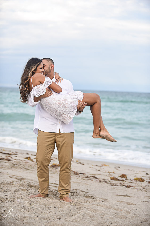 Foto von Strandverlobung in Florida wo Mann die Frau trägt am Strand